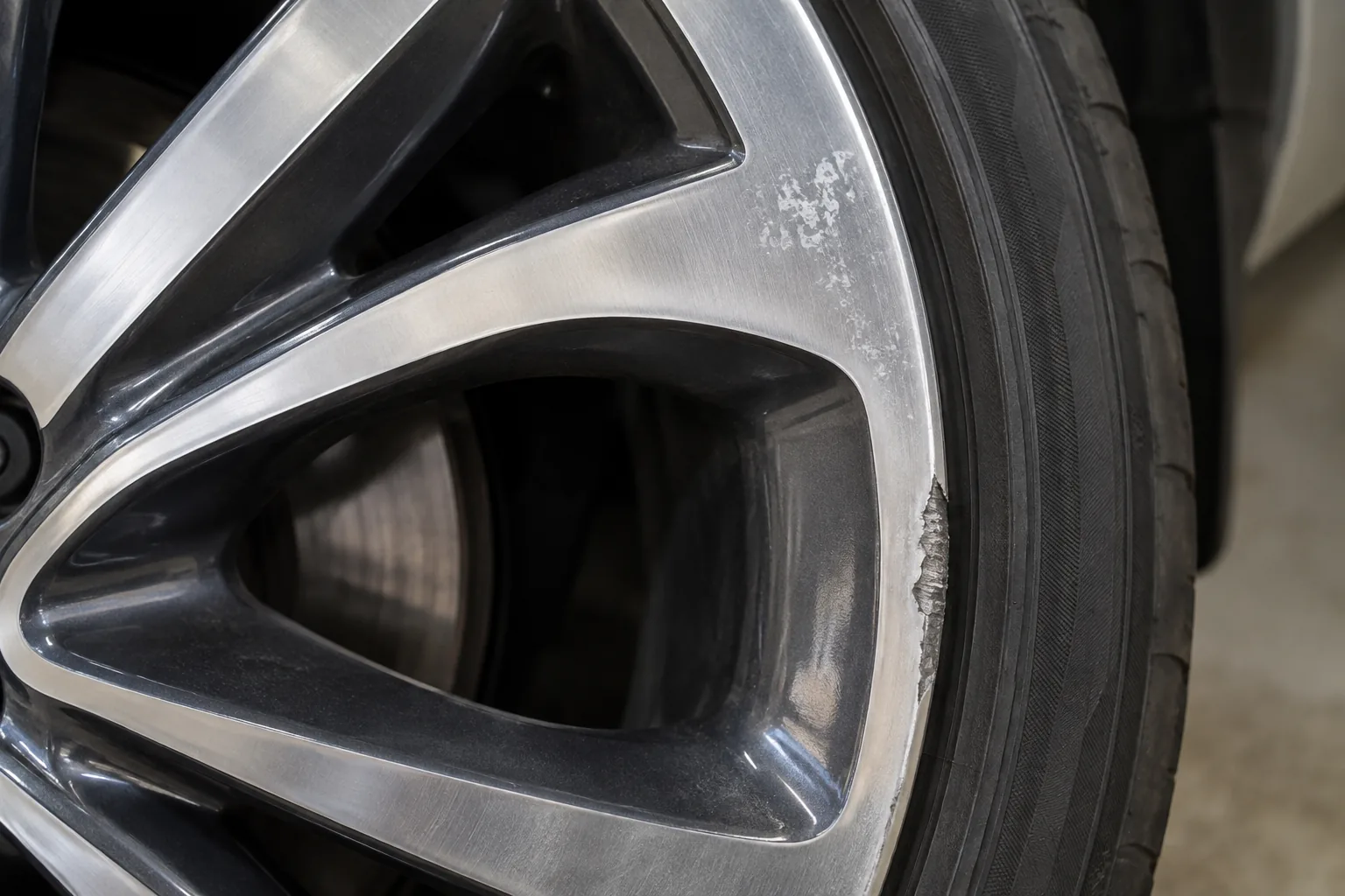 Illustration of a diamond-cut alloy wheel with curb damage and white marks on its machined face